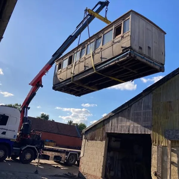 A railway carriage lifted in by crane beside the barn